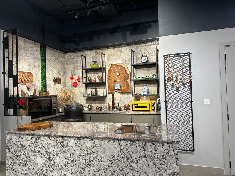 The Studio Kitchen: marble island with integrated induction, stone-tile feature wall and styled open shelving