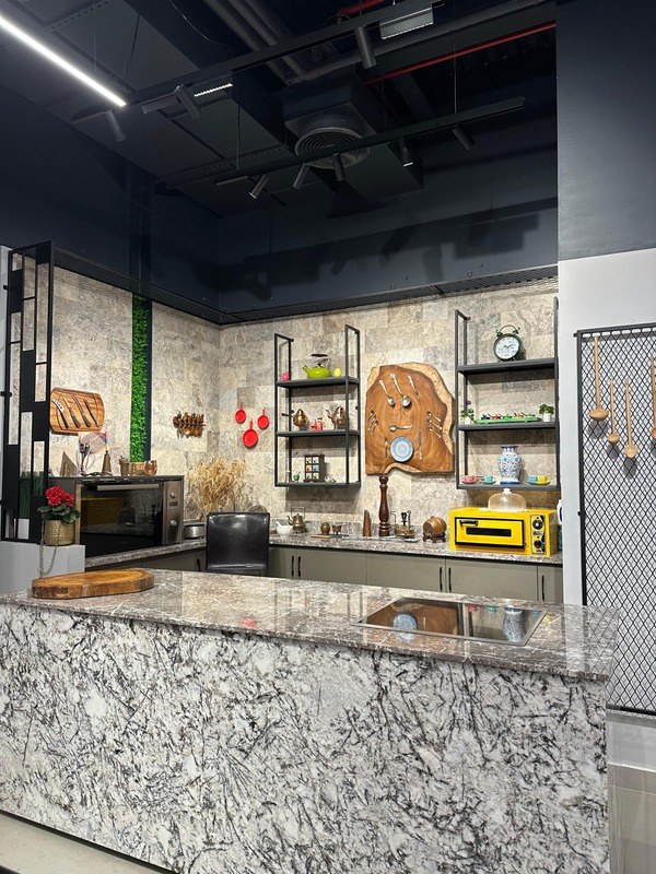 Wide view of the Studio Kitchen showing the marble island, feature wall and induction hob