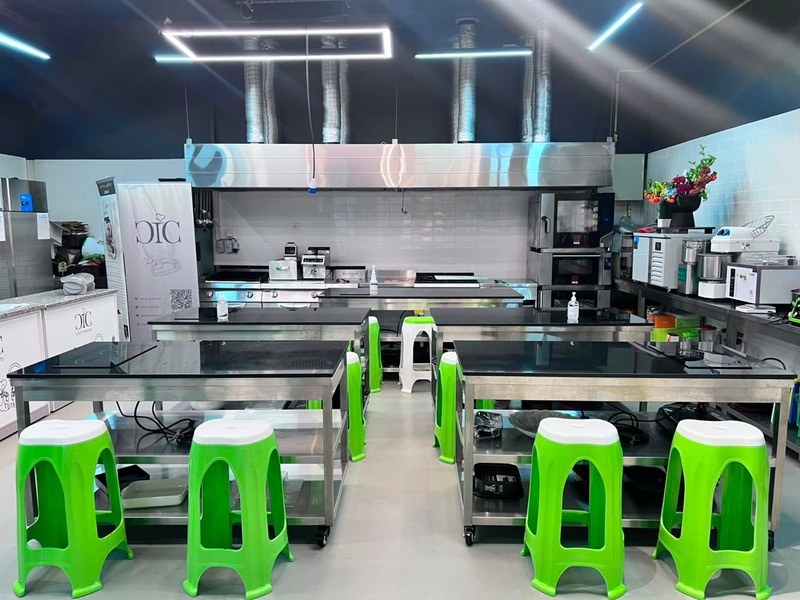 The Training Kitchen: mobile stainless steel induction tables under extraction hoods with the hot line behind